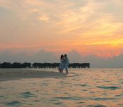 Couple Standing on White Sand Near Body of Water during Sunset